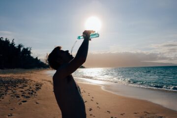 Homem bebendo água na praia